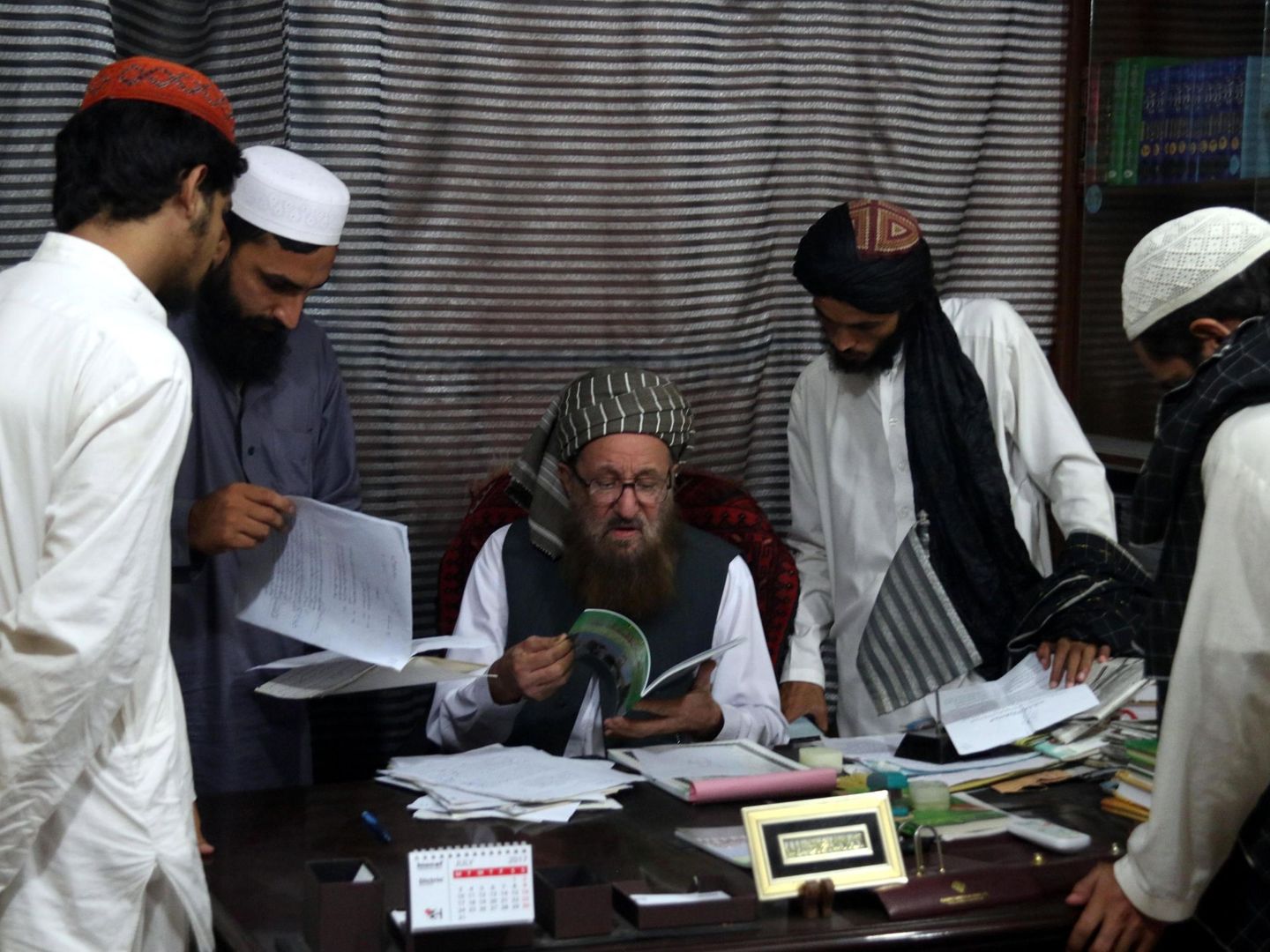 El maulana Sami ul Haq enseña un libro a unos estudiantes en la madrasa Darul Uloom Haqqania, bautizada como la 'universidad de la yihad' de los talibanes. (EFE)