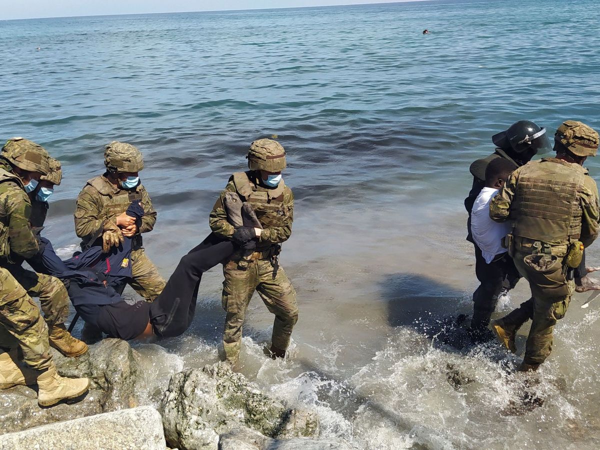 Foto: El Ejército ayuda a varios migrantes en la playa ceutí del Tarajal. (EFE)