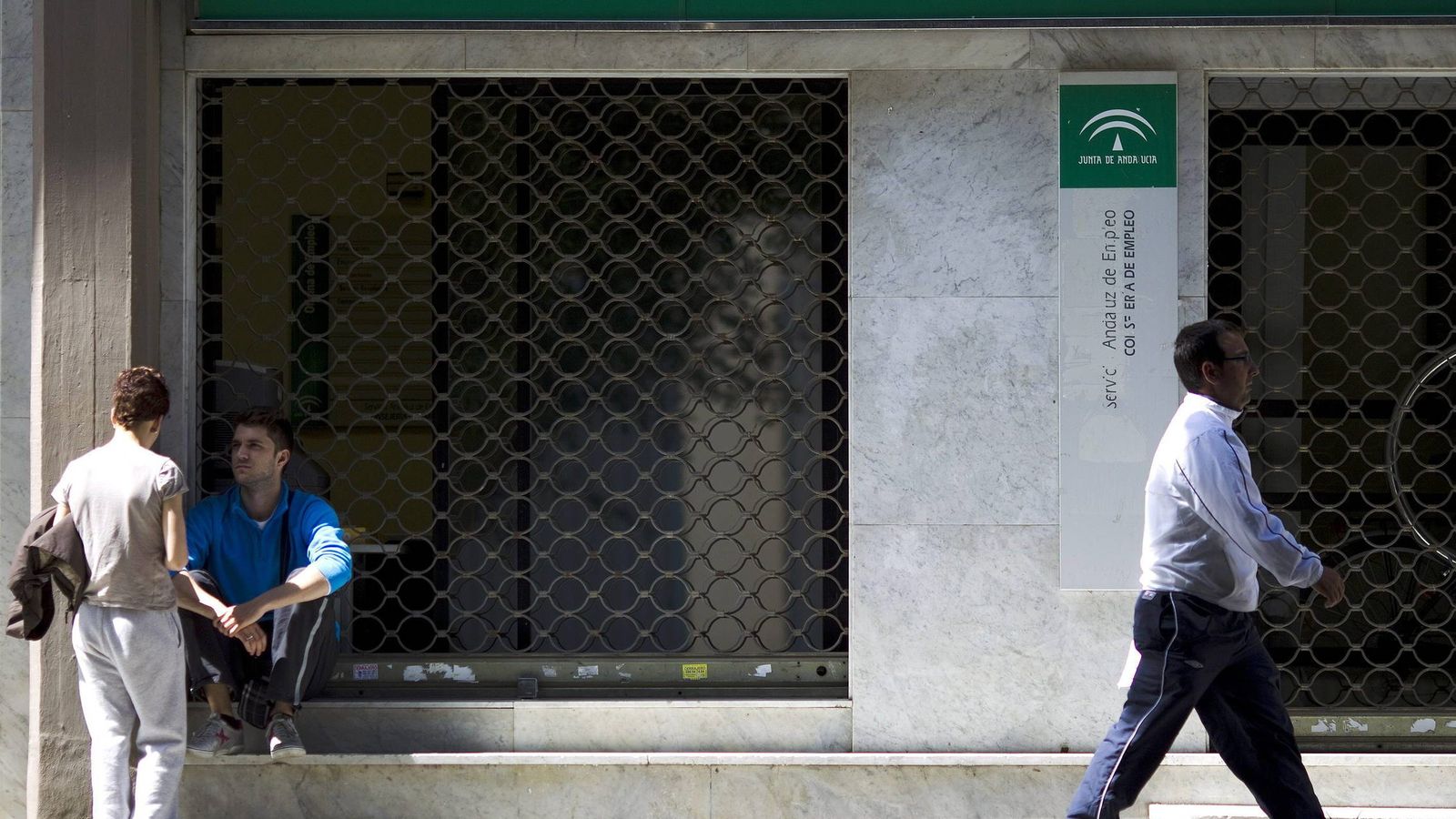 Foto: Unas personas en la puerta de una oficina de empleo de la Junta de Andalucía en Málaga. (EFE)