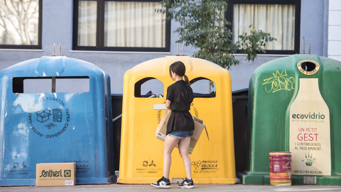 Un mujer deposita varios envases en un contenedor de reciclaje. (EFE/David Arquimbau Sintes)