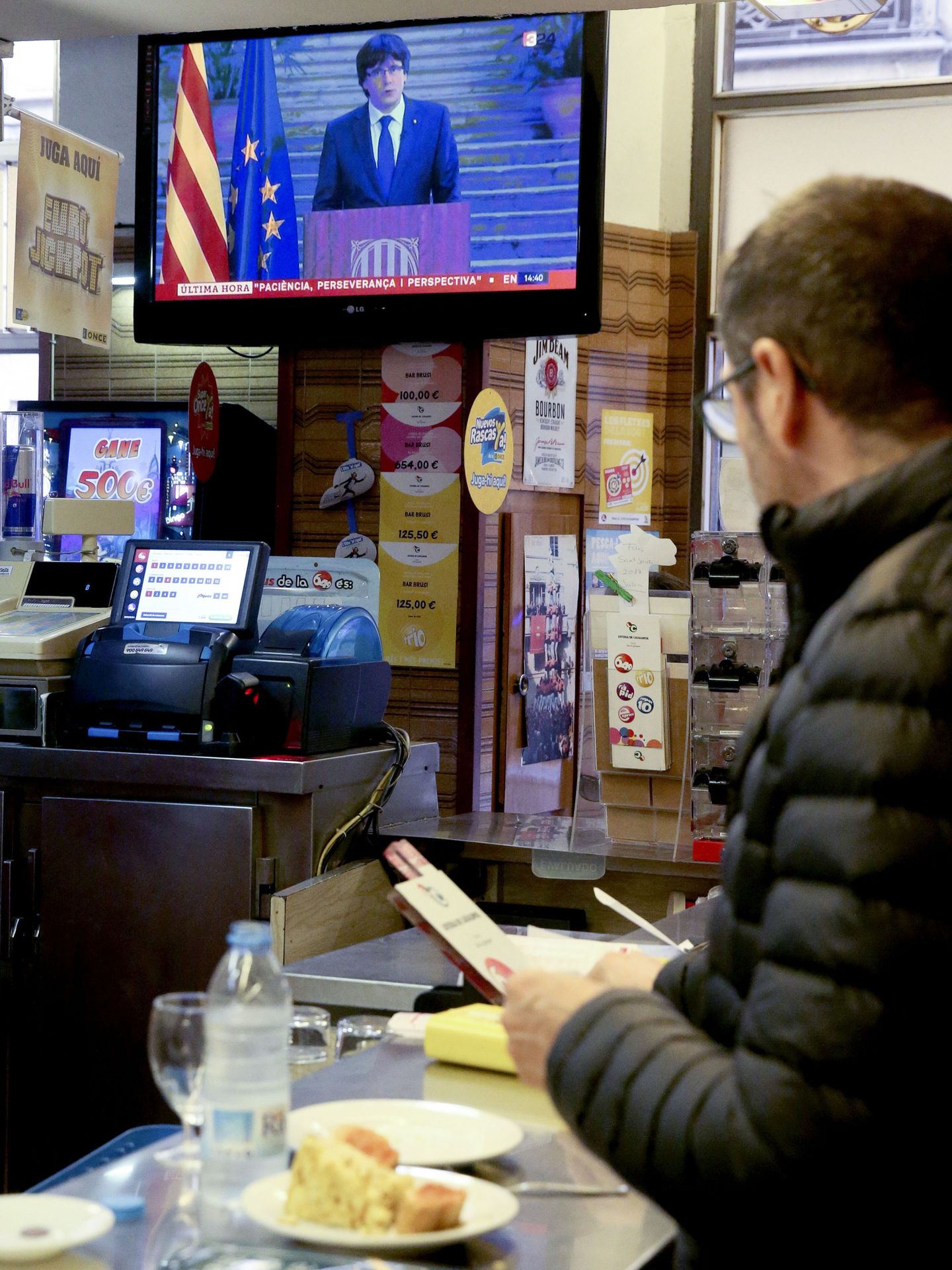 Un hombre sigue en la televisión de un bar la declaración de Carles Puigdemont. (EFE)