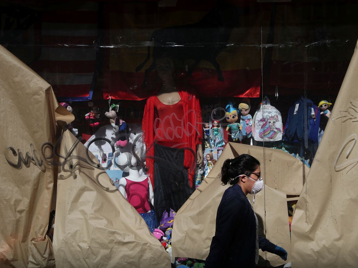 Foto: Una mujer pasa frente a una tienda cerrada, en mayo de 2020. (Reuters)