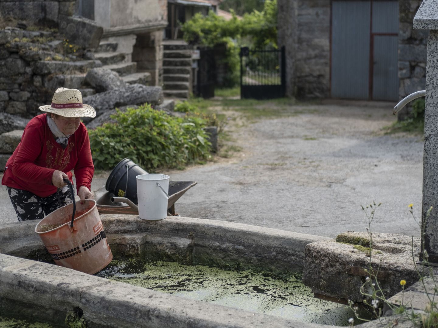 Una vecina del pueblo de San Mamede (Porqueira), recoge agua acumulada en un lavadero. (EFE/Brais Lorenzo)