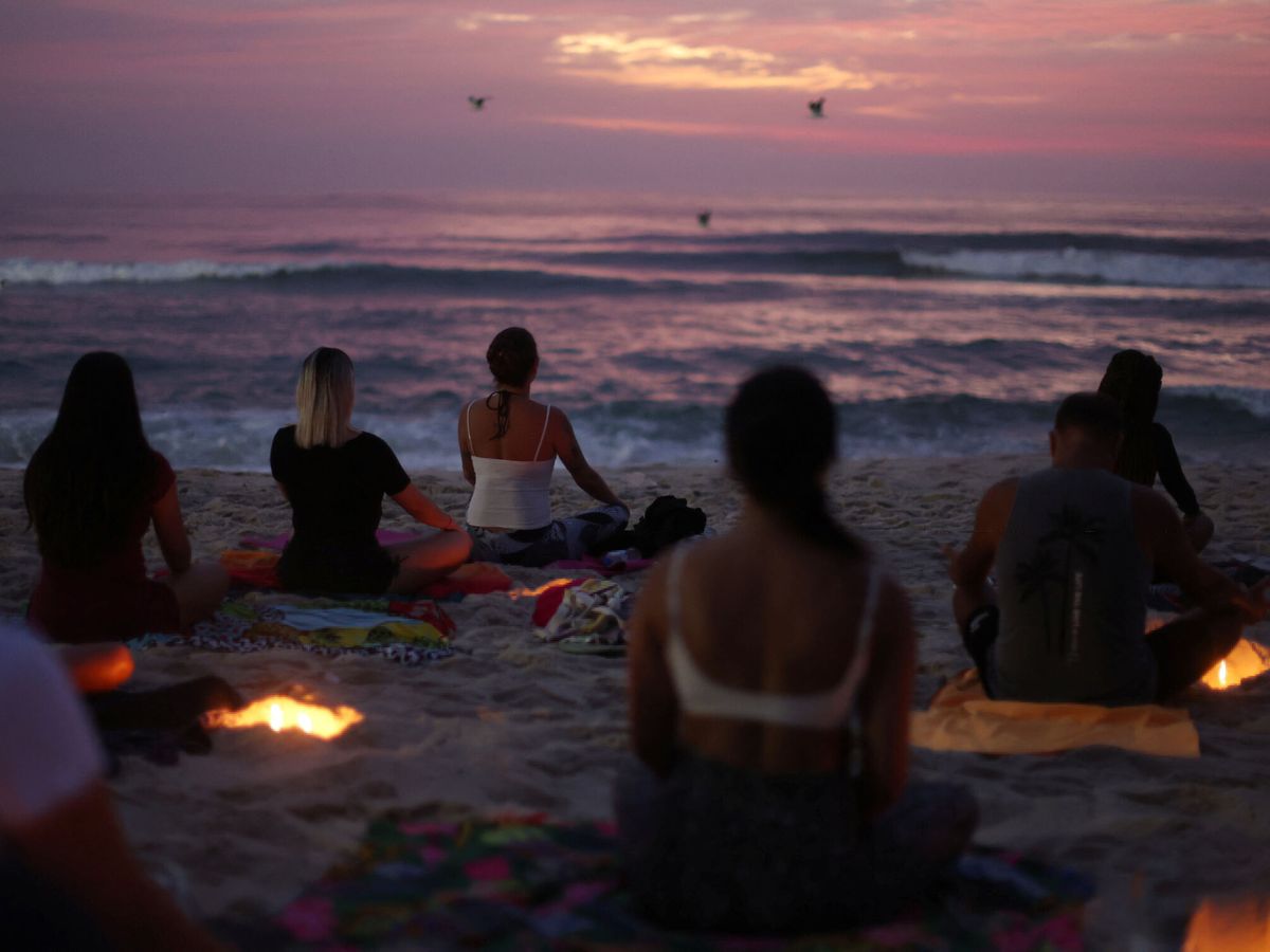 Foto: Un grupo de personas hace yoga en la playa. (Reuters/Pilar Olivares)