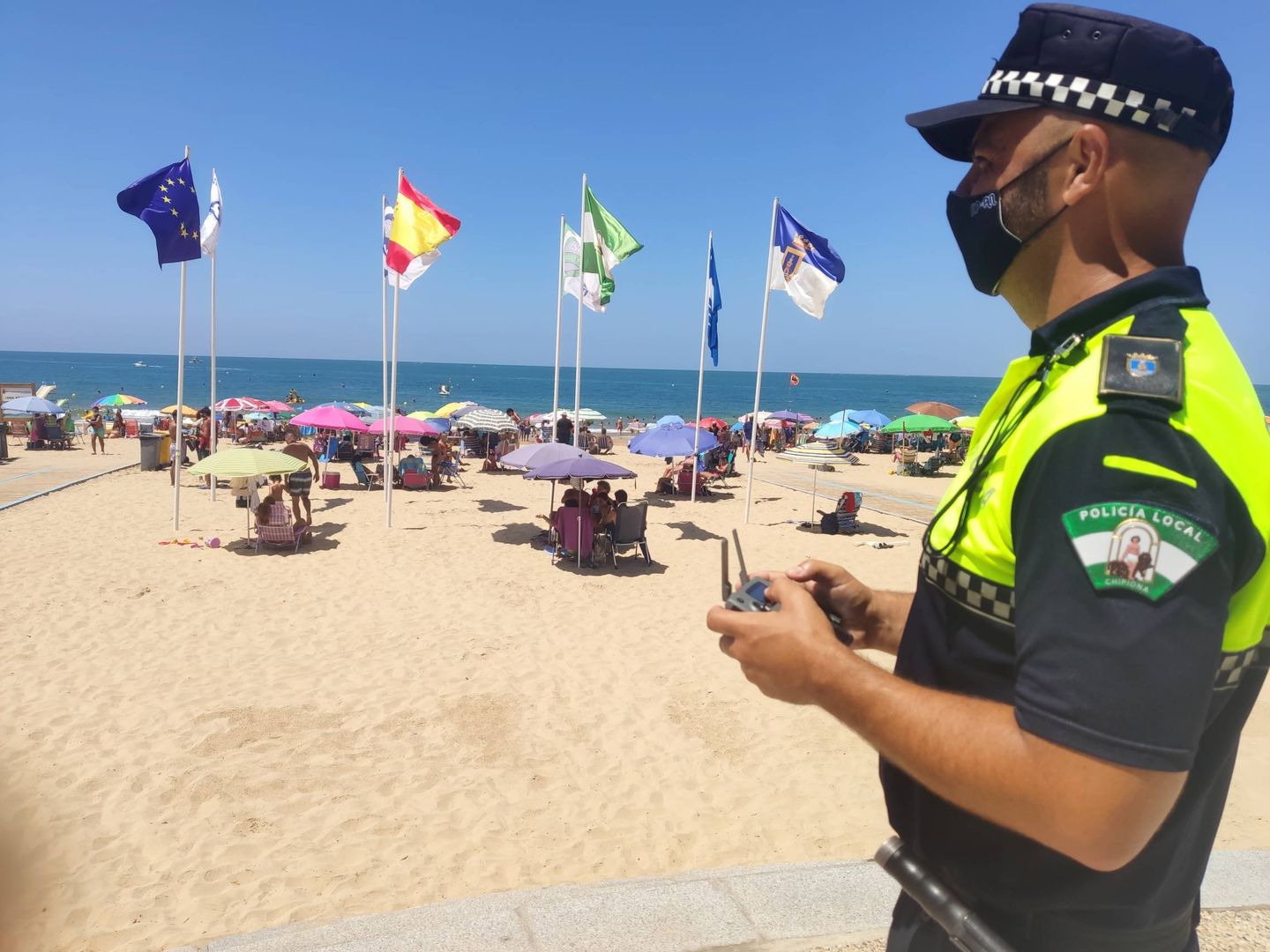 Un policía local de Chipiona vigila con un dron el aforo de las playas durante la pandemia.