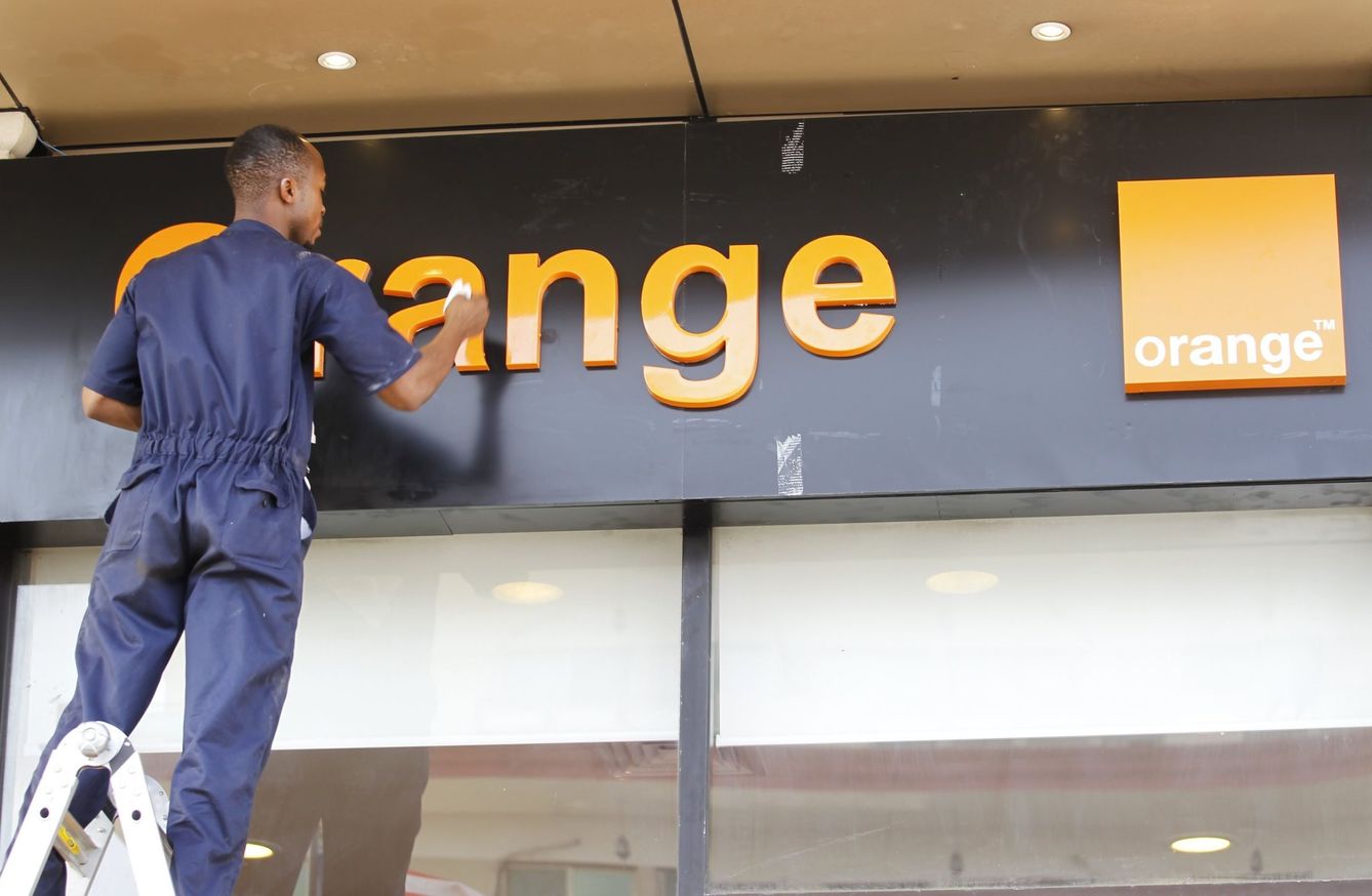 Un operario limpia un cartel de Orange. (EFE)