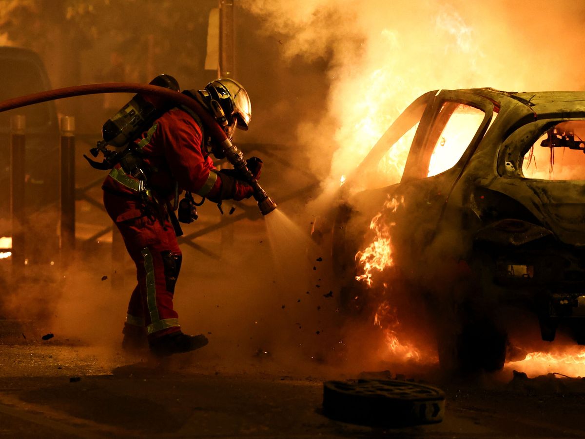 Foto: Un bombero junto a un vehículo incendiado durante las protestas en Francia. (Reuters/Stephanie Lecocq)