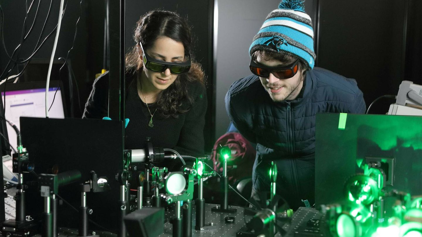Los candidatos doctorales Sara Makarem Hoseini y Daniel Hirt con el láser que genera el rayo de plasma. (UV) 