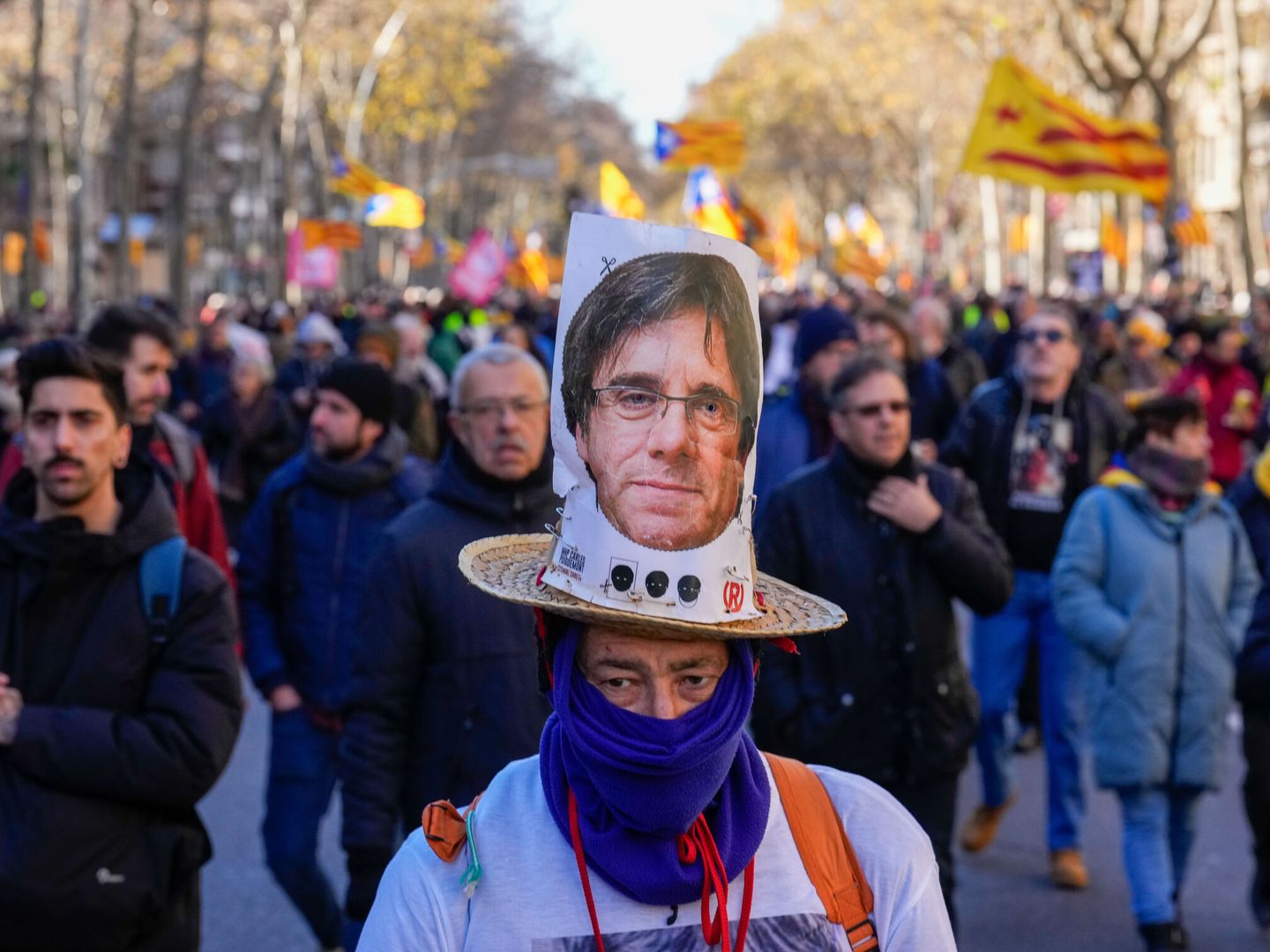 Un activista lleva un retrato de Carles Puigdemont mientras participa en una manifestación contra la cumbre hispanofrancesa en Barcelona. (EFE/Alejandro García)