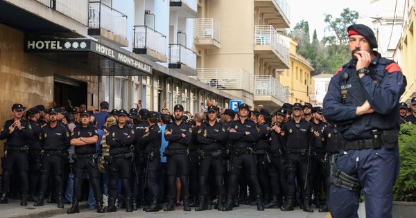 Foto: Un Mosso d'Esquadra frente a un grupo de agentes de la Policía Nacional a las afueras del hotel en el que se alojaban. (Reuters)
