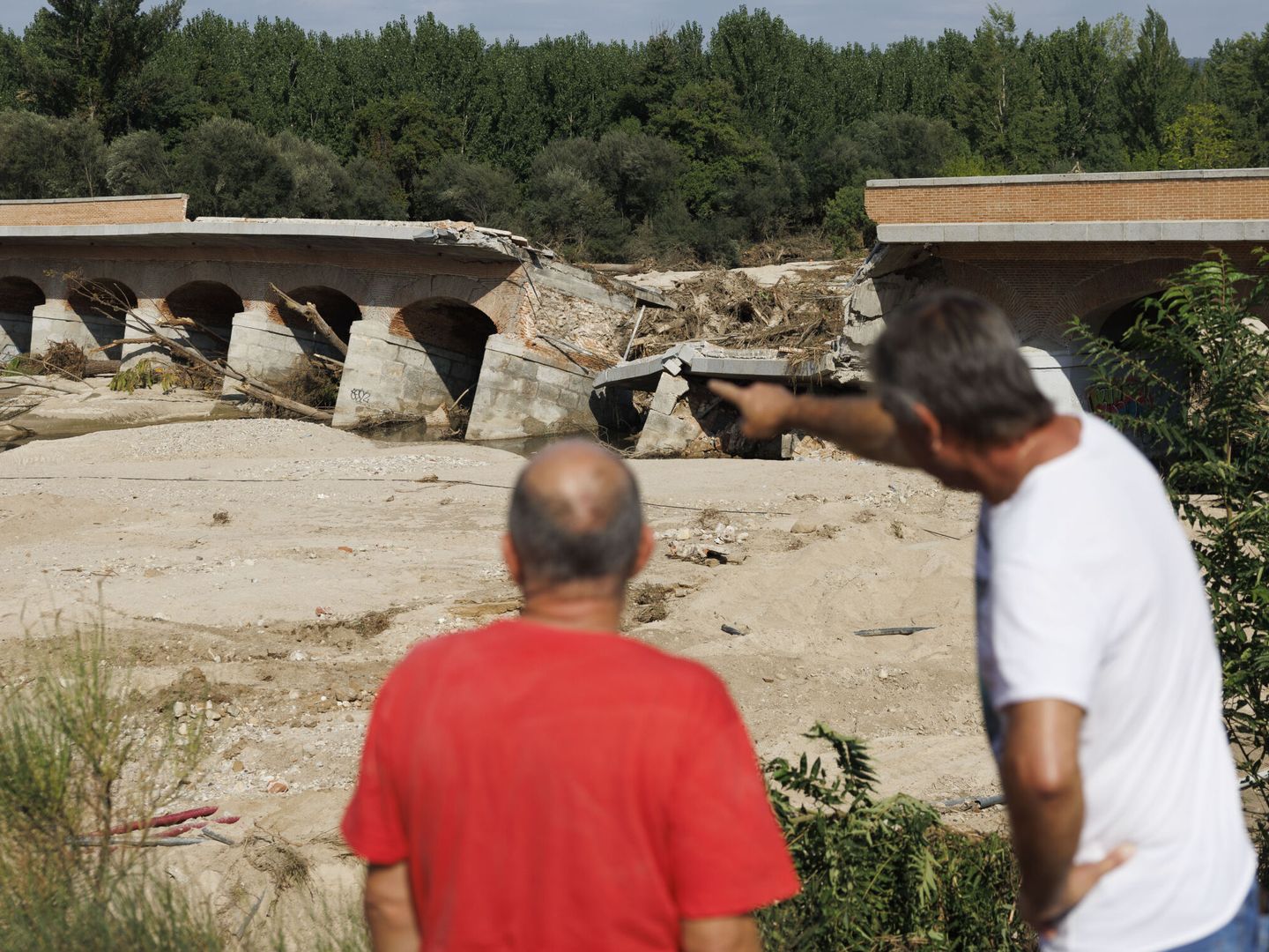 Dos hombres apuntan al destrozado Puente de la Pedrera, en Aldea del Fresno, Madrid. (EFE/Sergio Pérez)