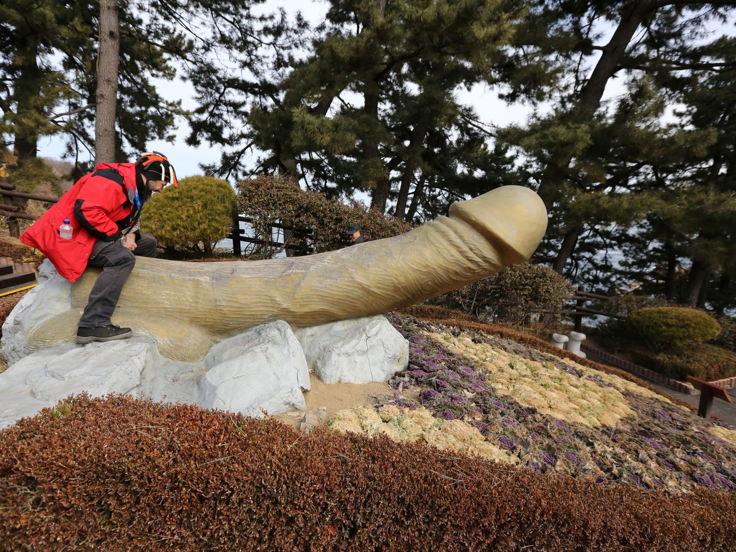 Un visitante se sienta sobre una escultura fálica en el parque Haesindang de la ciudad de Sinnam, Corea del Sur. (EFE/EPA/Tatyana Zenkovich)