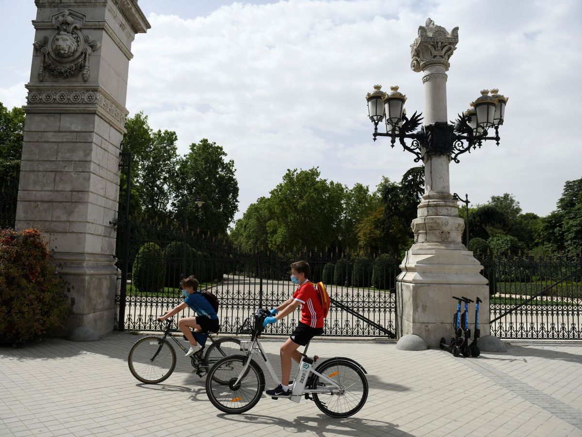 Foto: Dos jóvenes montan en bici en el exterior del parque del Retiro en Madrid. (EFE)