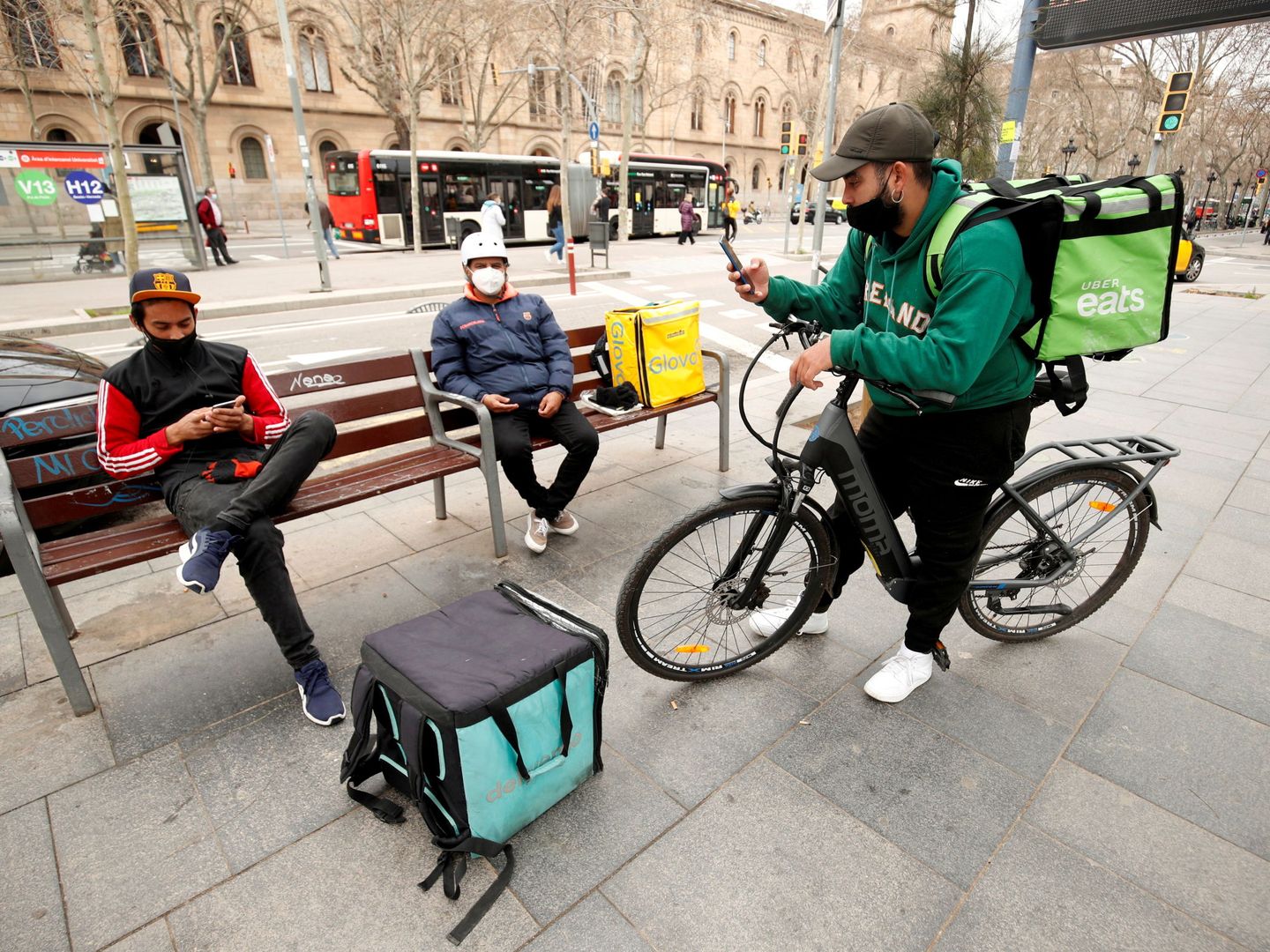 Repartidores de Deliveroo, Glovo y Uber Eats en la plaza Universitat de Barcelona.