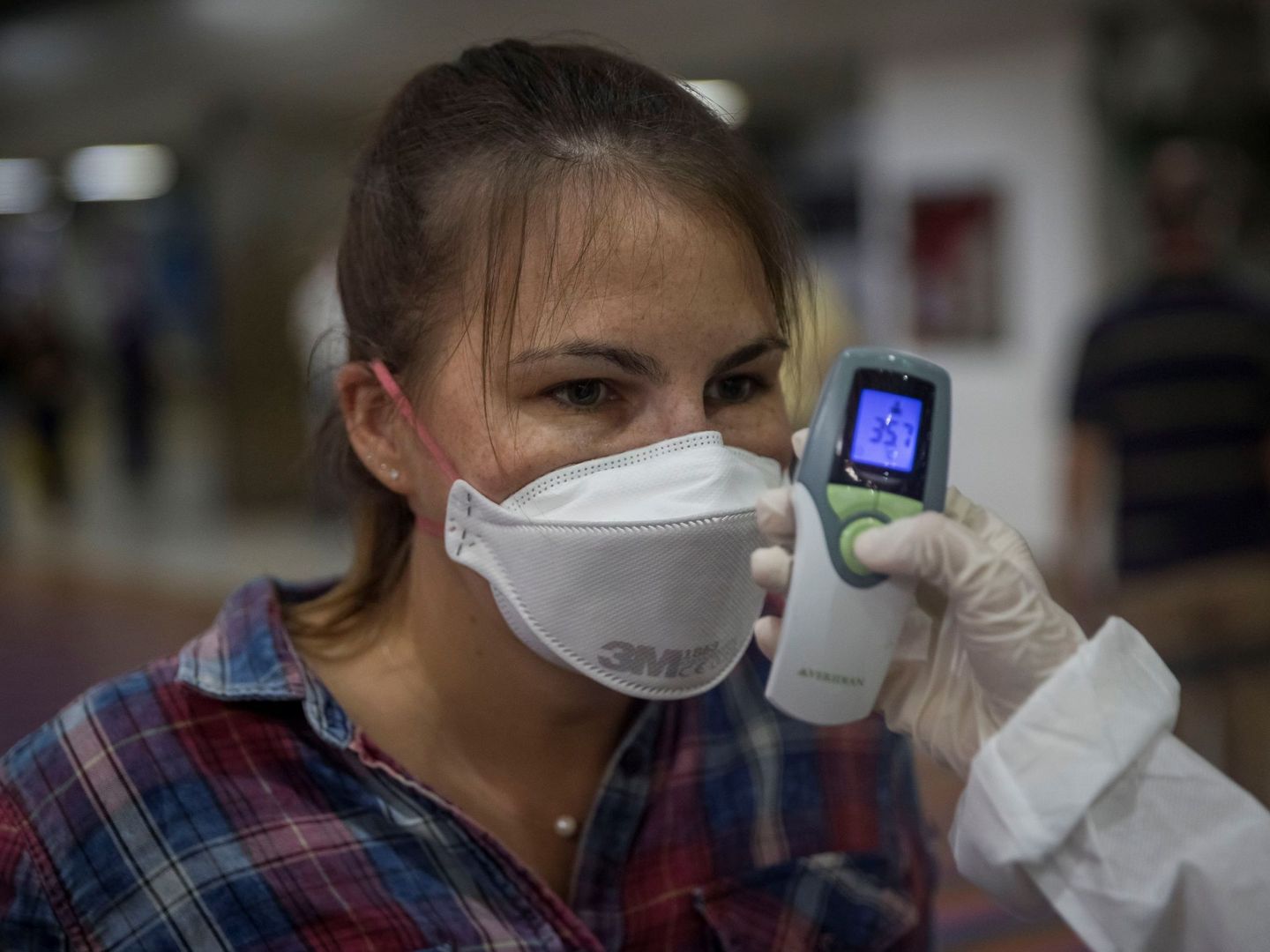 Un trabajador sanitario toma la temperatura de ciudadanos europeos en el Aeropuerto Internacional Simón Bolívar de Maiquetía, en La Guaira, Caracas (Venezuela). (EFE)