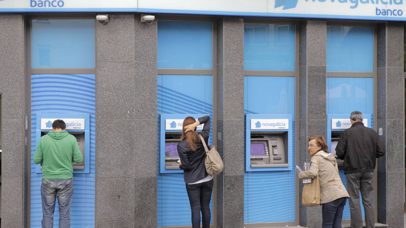 Foto: Usuarios retiran dinero de varios cajeros en una sucursal bancaria. (EFE)