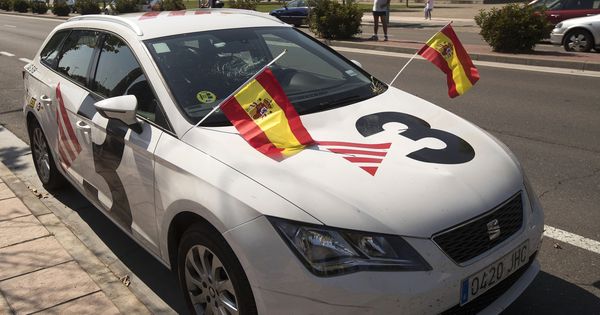 Foto: Un coche de TV3 con la luna rota y en el que los manifestantes han colocado dos banderas de España. (EFE)