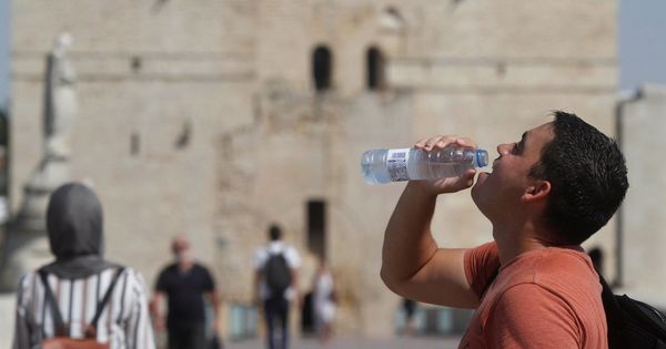 Foto: Un joven bebe agua mientras pasea por el Puente Romano de Córdoba. (EFE)