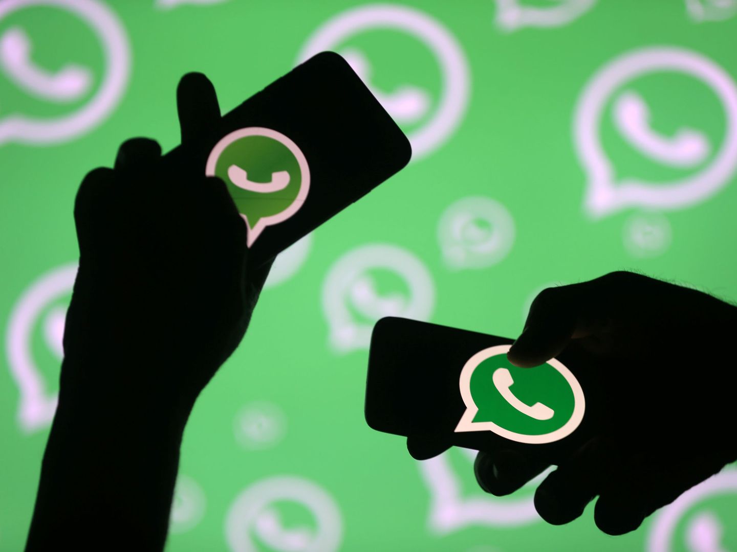 Men pose with smartphones in front of displayed Whatsapp logo in this illustration September 14, 2017. REUTERS Dado Ruvic