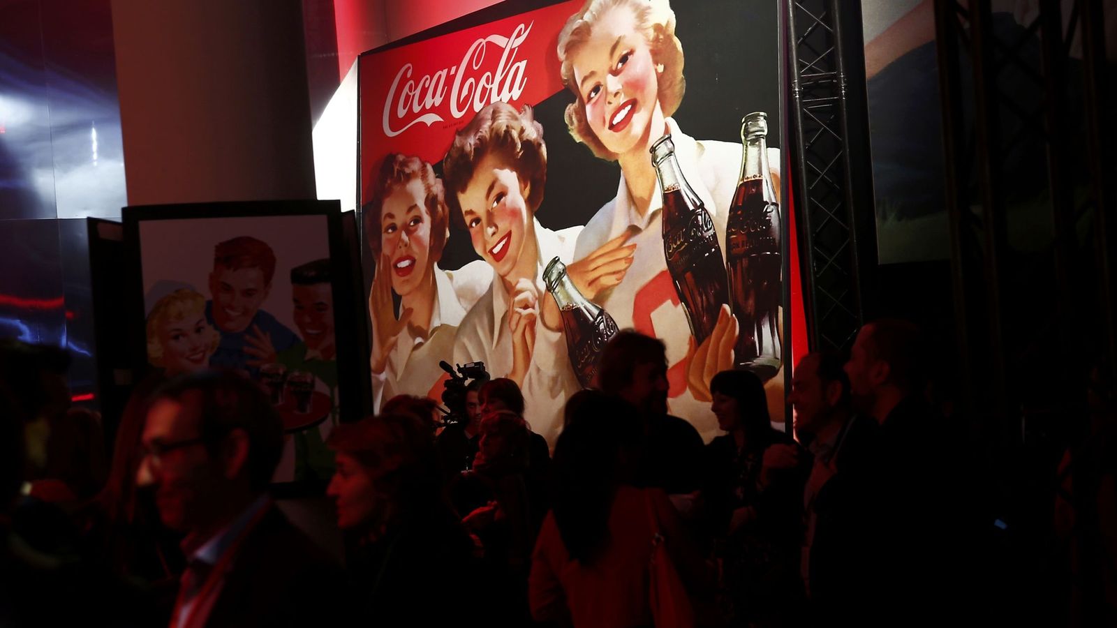 Foto: Presentación de Coca-Cola con el logo al fondo.