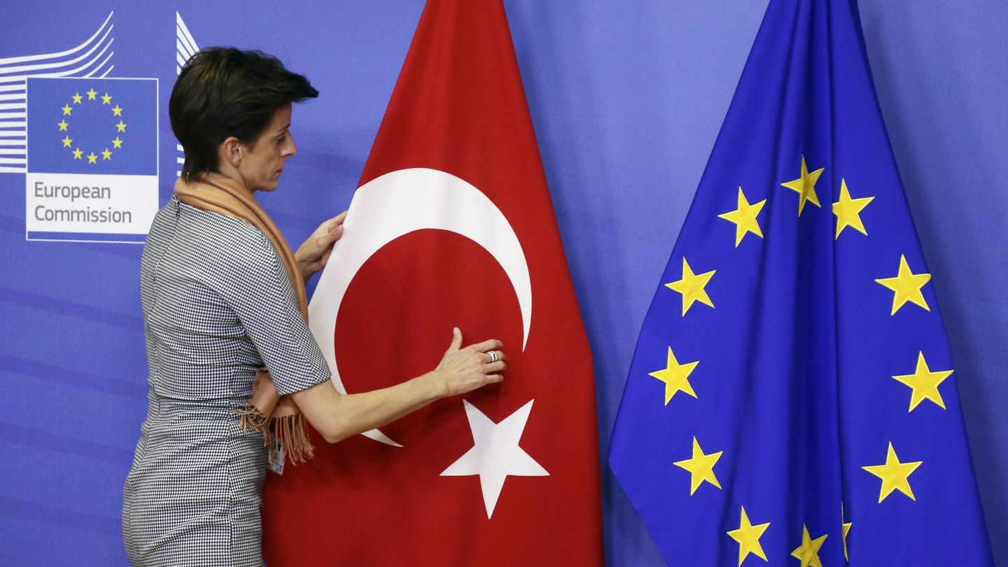 Una trabajadora de la Comisión Europea sitúa una bandera turca junto a una europea antes de una visita de un cargo turco al Ejecutivo comunitario. (Reuters)