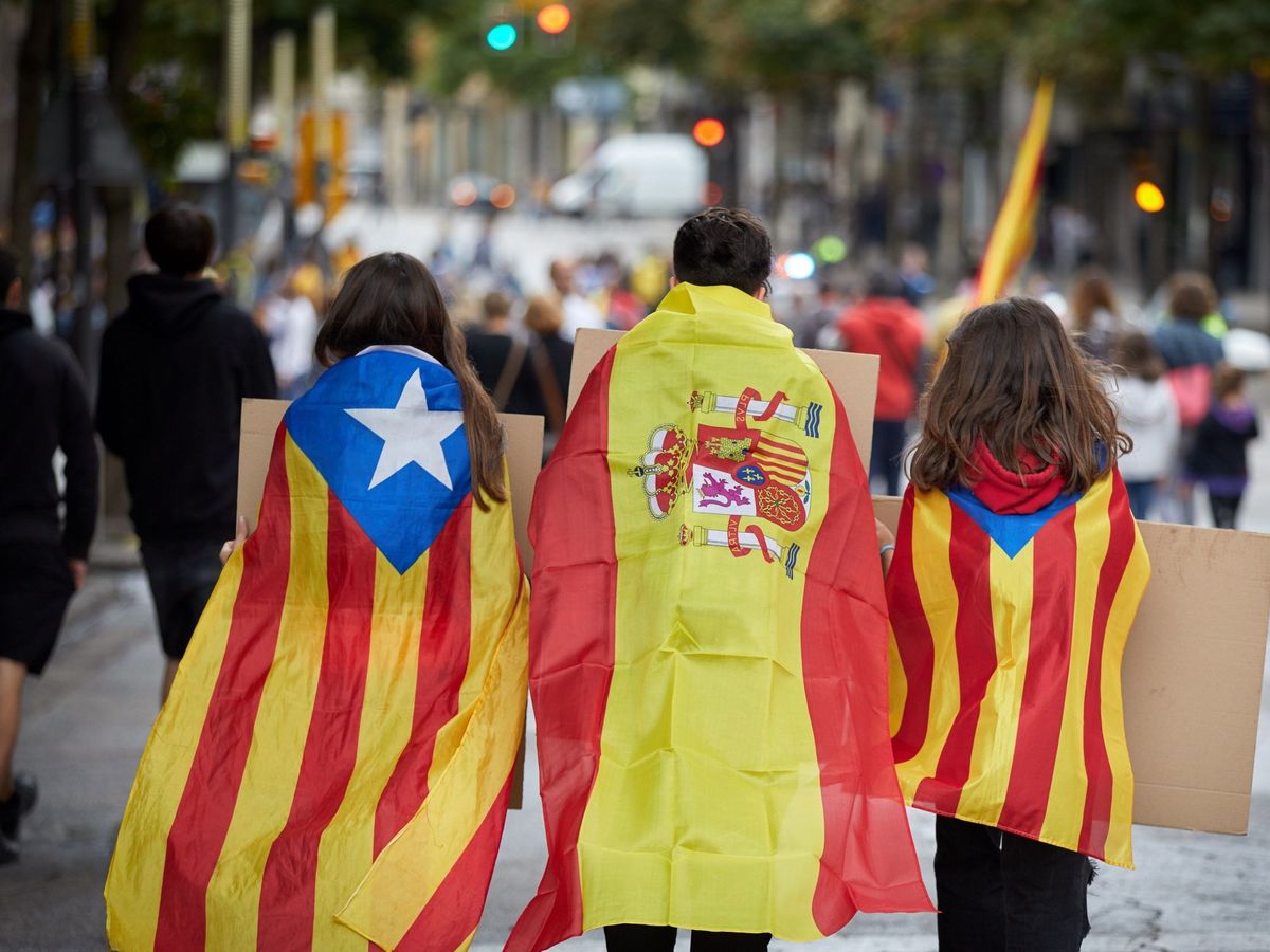 Foto: Foto de archivo de tres jóvenes ataviados con banderas de España y esteladas. (EFE/David Borrat)