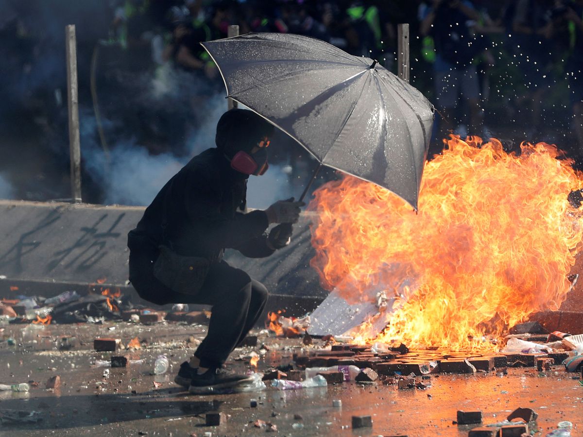 Foto: Un manifestante se protege bajo un paraguas durante el caos de las protestas. (REUTERS)
