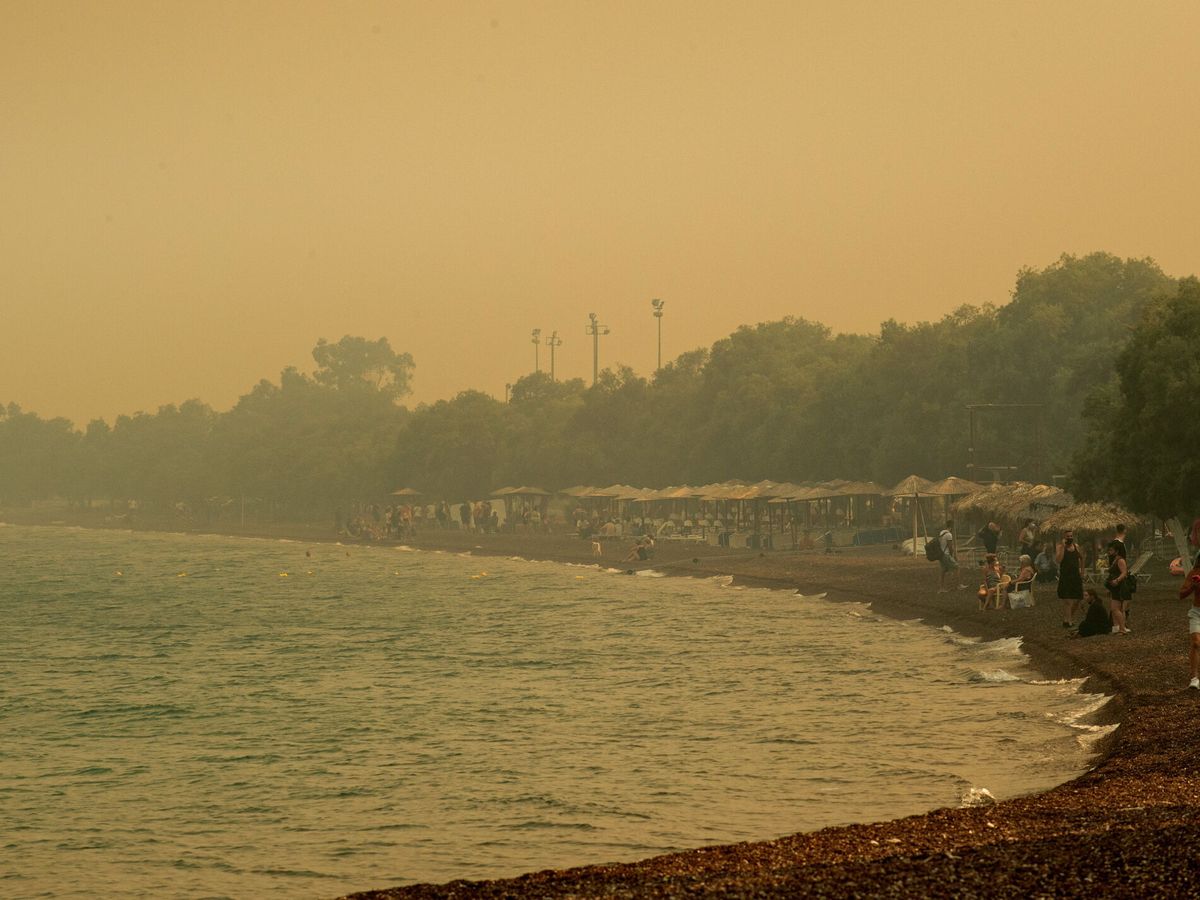 Foto: Personas esperan en una playa a ser evacuadas en barcos durante un incendio forestal en Nea Anchialos, cerca de Volos. (EFE/Ikonomou Vassilis)