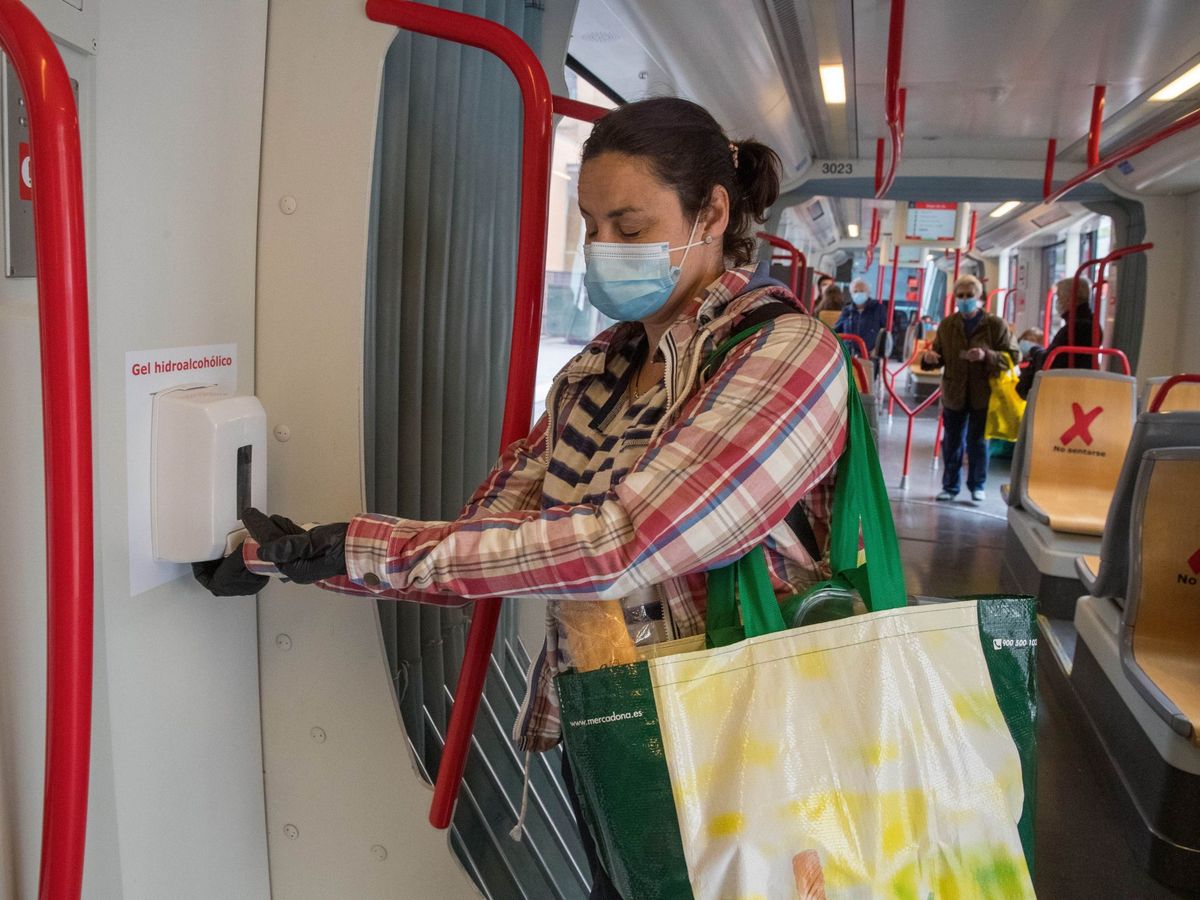Foto: Una viajera utiliza gel hidroalcohólico instalado en un autobús de Zaragoza. (EFE)