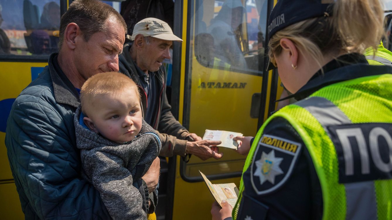 Foto: Policias revisan documentos de identificacion de refugiados en el estacionamiento de un centro comercial, hoy en Zaporiya (Ucrania). (EFE/ Miguel Gutiérrez)