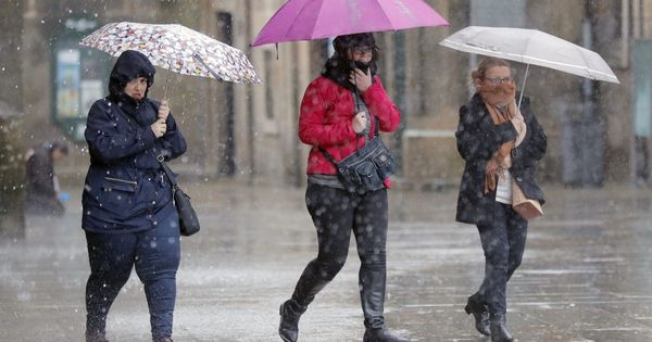 Foto: Varias personas transitan bajo la lluvia la plaza del Obradoiro, en Santiago de Compostela. (EFE) 