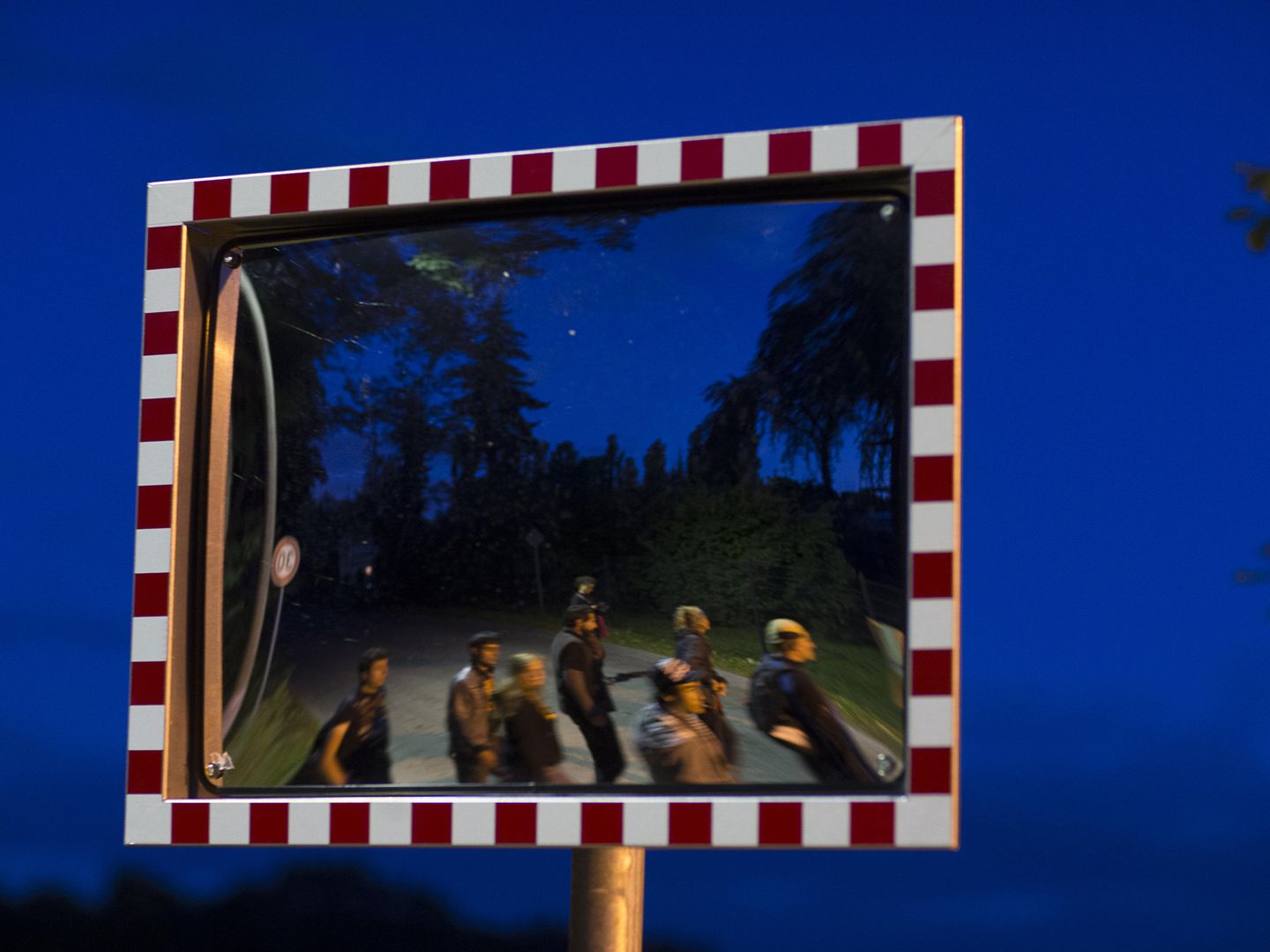 Refugiados reflejados en un espejo durante una protesta en el pueblo alemán de Petzow (Reuters).