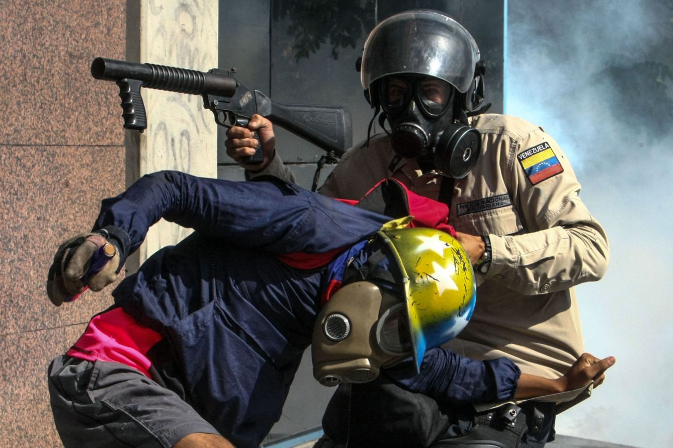 Un agente antidisturbios agarra a un manifestante mientras dispara gases lacrimógenos en Caracas, el 20 de mayo de 2017. (EFE)