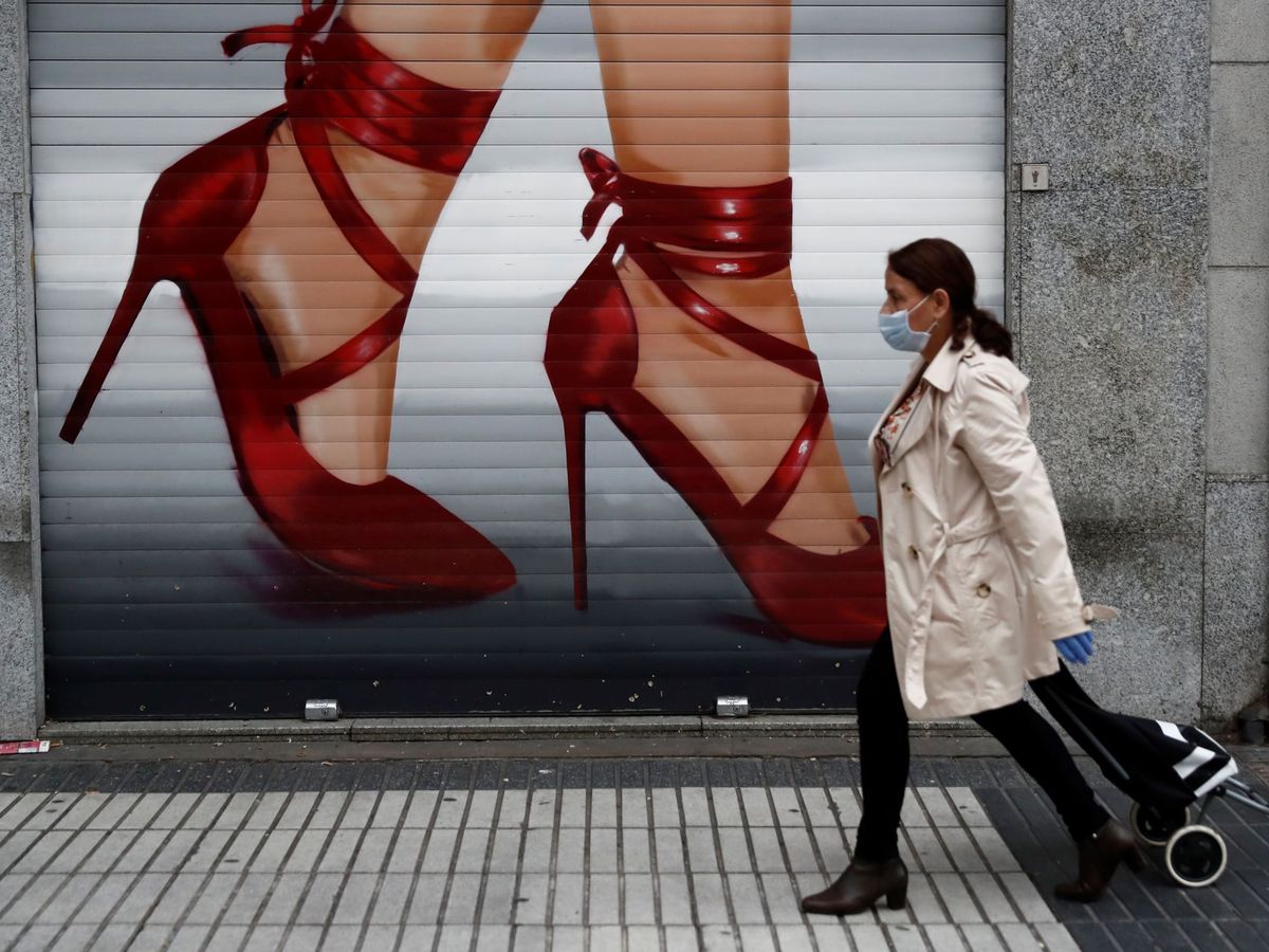 Foto: Una mujer que va a hacer la compra pasa ante el cierre de un negocio cerrado en Madrid. (EFE)