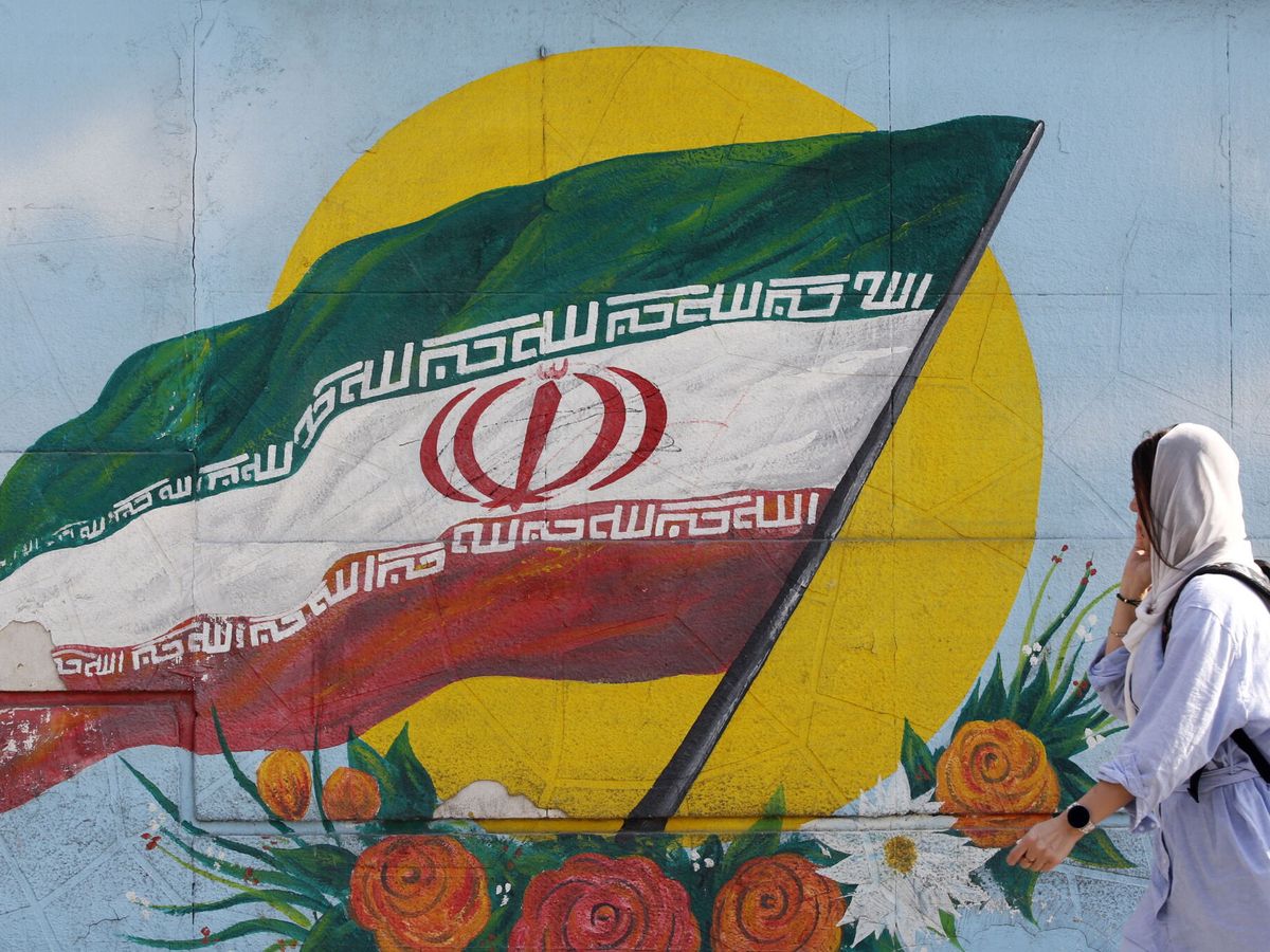 Foto: Una mujer pasa frente a un grafiti con la bandera de Irán. (EFE/EPA/Abedin Taherkenareh)