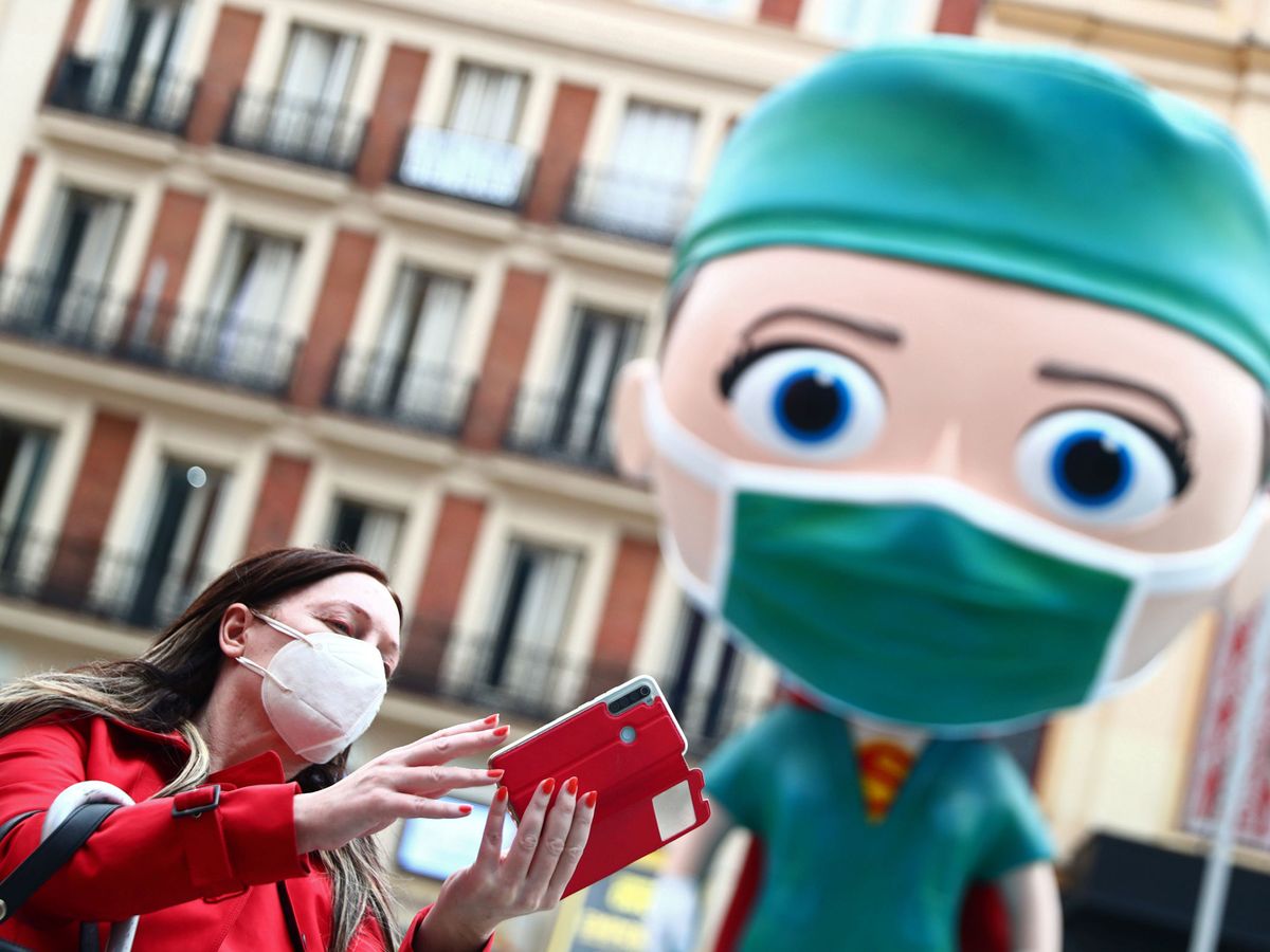 Foto: Una mujer se hace una foto con la estatua en homenaje a los sanitarios de Madrid (REUTERS)