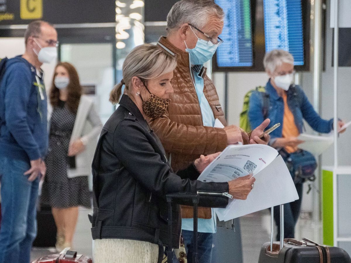 Foto: Unos viajeros revisan sus papeles en el aeropuerto de Palma de Mallorca. (EFE)