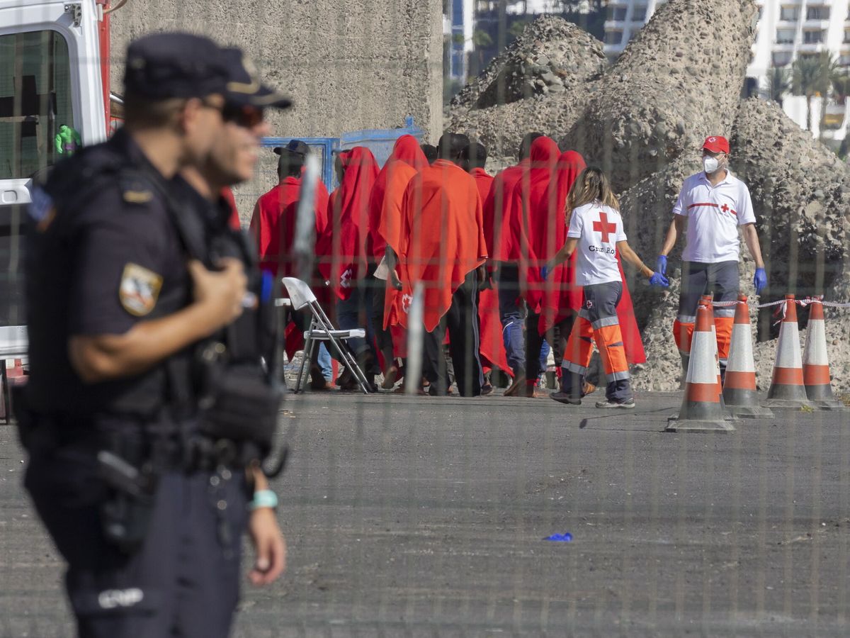 Foto: Dos policías, ante un grupo de inmigrantes rescatados en Canarias la semana pasada. (EFE/Quique Curbelo)