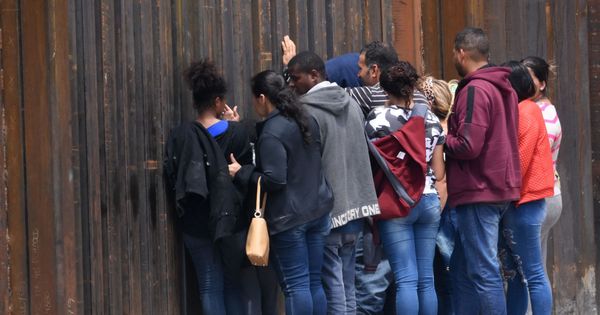 Foto: Migrantes centroamericanos se asoman a través del muro fronterizo, en Ciudad Juárez, México. (EFE)