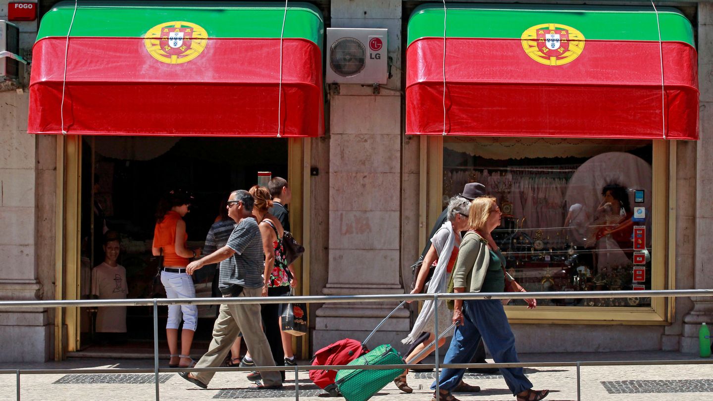 Turistas y residentes pasan por delante de una tienda en el centro de Lisboa. (Reuters)