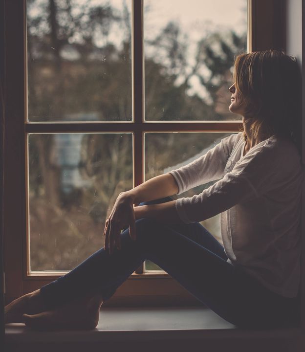 Foto: Una mujer se relaja mirando por la ventana. (iStock)