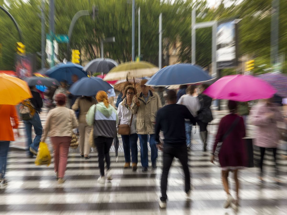 Foto: Varias personas se protegen de la lluvia caída este jueves en Zaragoza. (EFE/Javier Belver)
