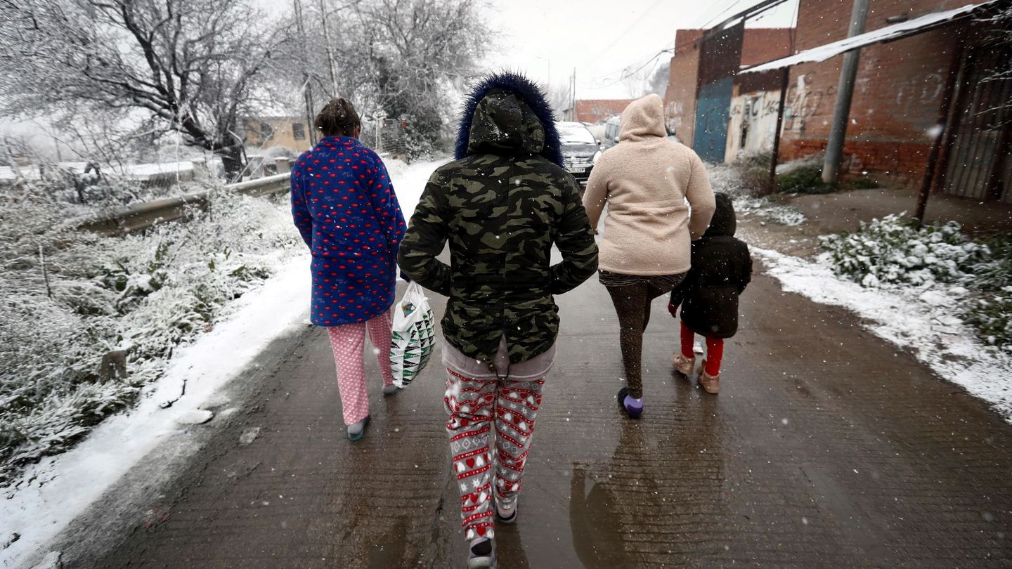 Varios residentes del asentamiento de la Cañada Real caminan bajo la nieve. (EFE) 