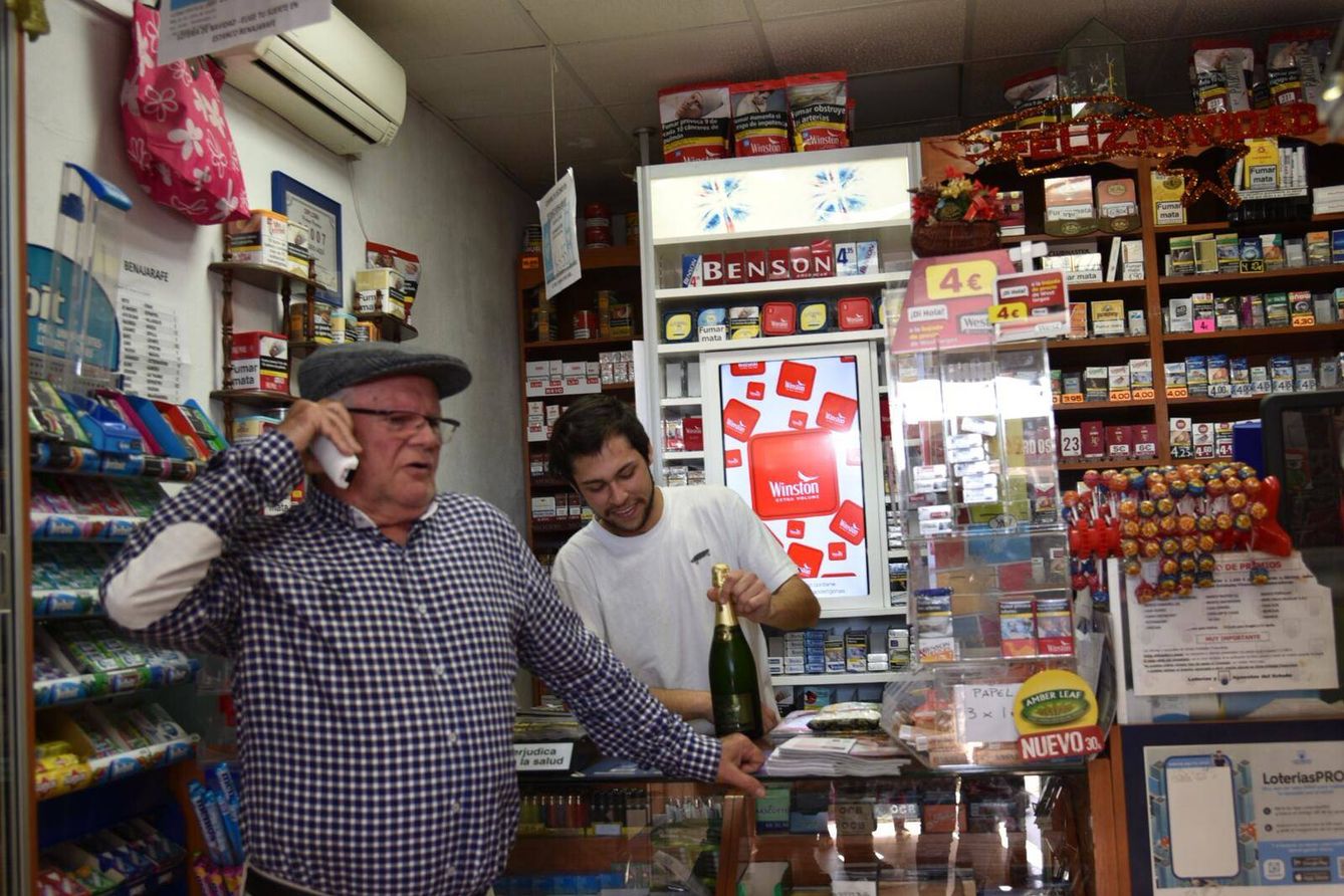 Pepe hablando por teléfono, junto a Douglas, el empleado de la administración de lotería. (Toñi Guerrero)