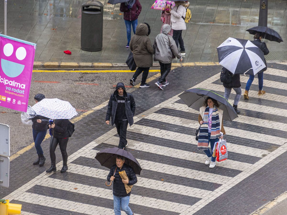Foto: Peatones se protegen con paraguas de la lluvia en Palma de Mallorca. (EFE/Cati Cladera)