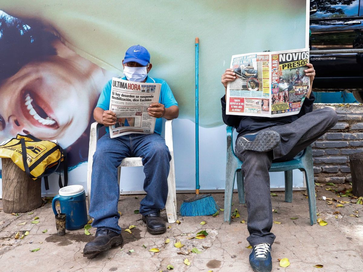 Foto: Dos hombres leen el periódico al aire libre este lunes, en Asunción (Paraguay). (EFE)