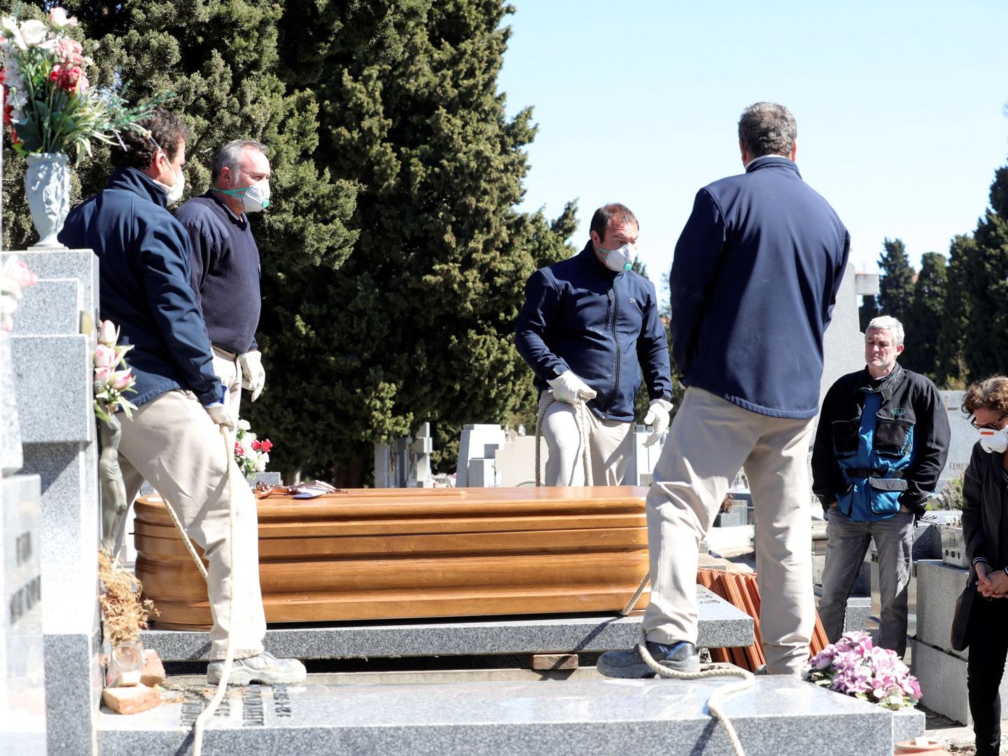 Operarios del cementerio de la Almudena de Madrid entierran un féretro la semana pasada. (EFE)
