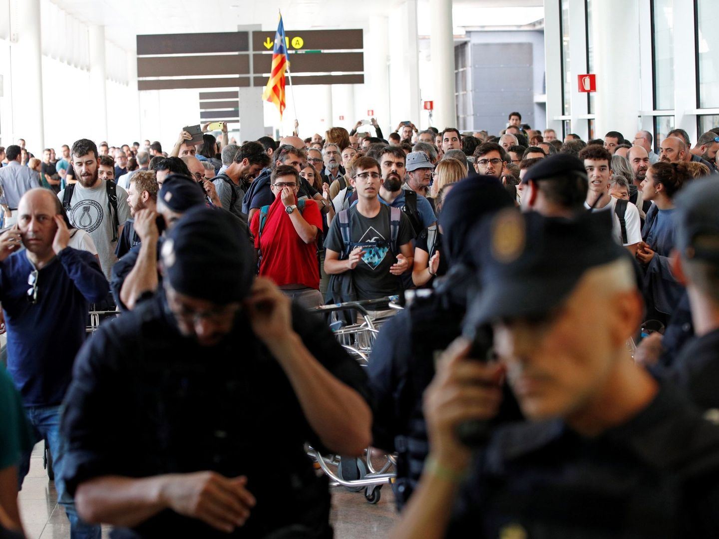 Agentes de los Mossos d'Esquadra y de la Policía Nacional controlan el acceso de personas a la terminal 1 del Aeropuerto de El Prat. (EFE)