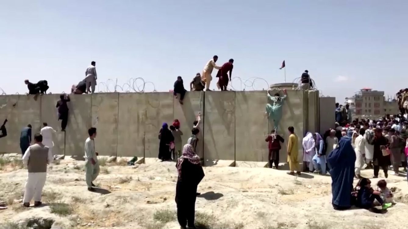 Foto: Unas personas escalan un muro de alambre de espino para entrar en el aeropuerto de Kabul, Afganistán. (Reuters)