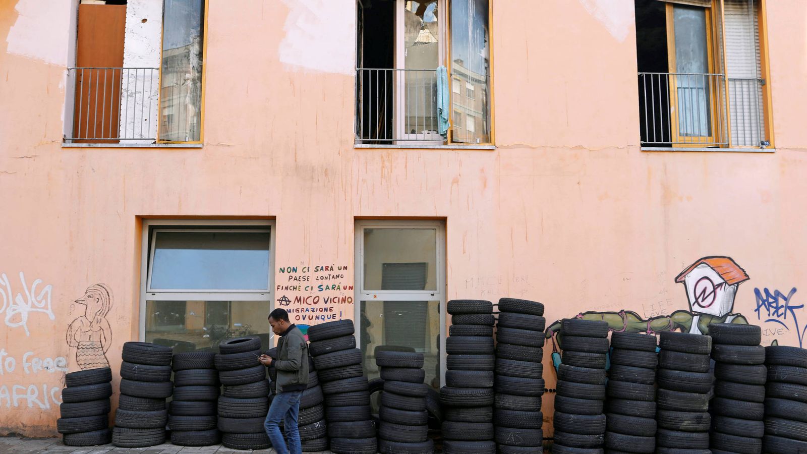 Foto: Un hombre pasa frente a un edificio ocupado en la antigua Villa Olímpica de Turín, en enero de 2018. (Reuters)